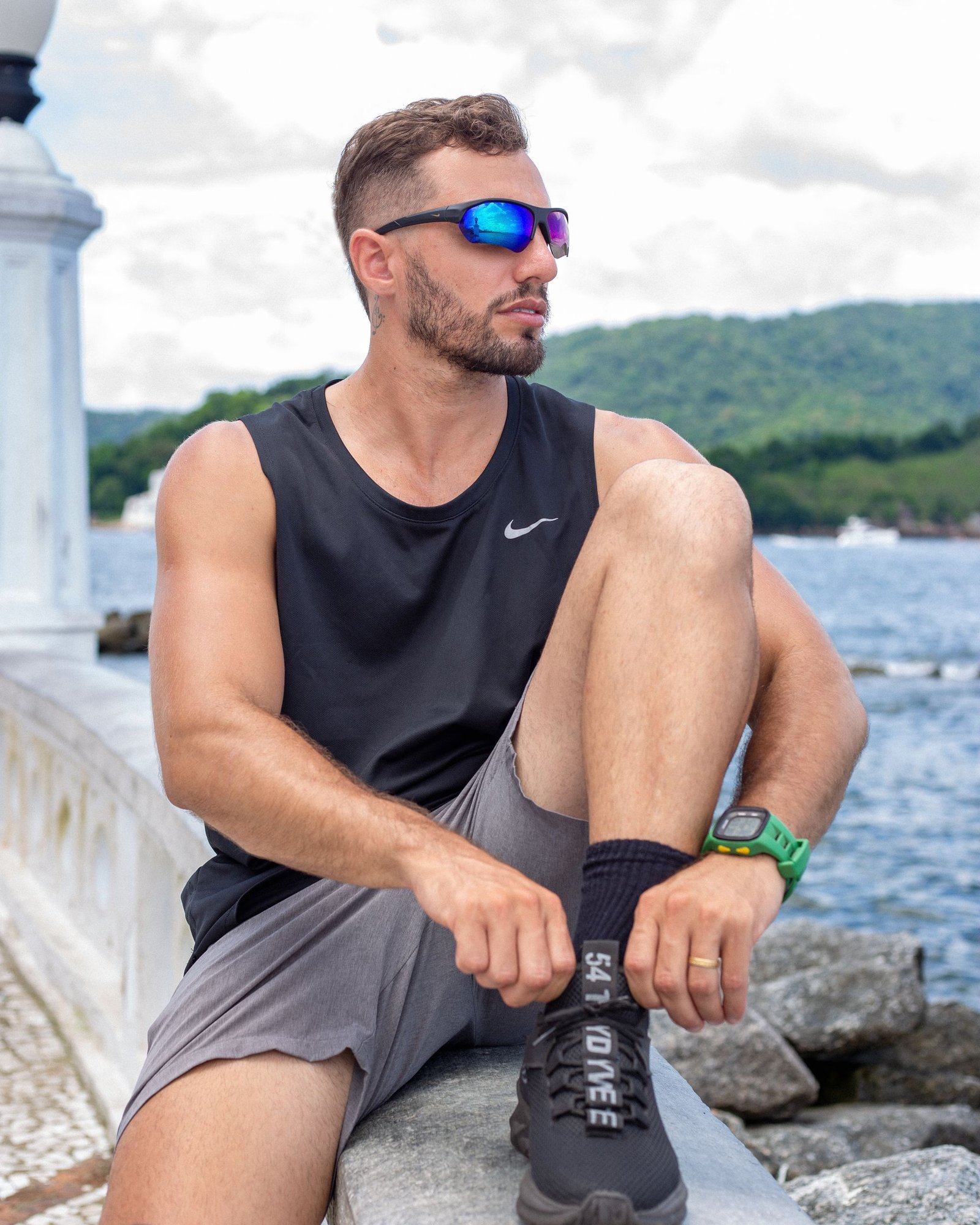 A man in sportswear relaxes by a serene lake, showcasing modern outdoor lifestyle.